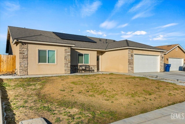 view of front of property featuring a garage, a front lawn, and solar panels