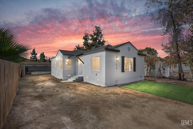 back house at dusk featuring a lawn