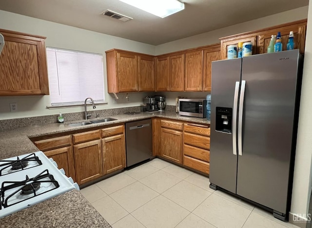 1941 Vassar St, Delano, CA 93215 - kitchen with stainless steel appliances, a sink, brown cabinets, light tile patterned floors, and dark countertops