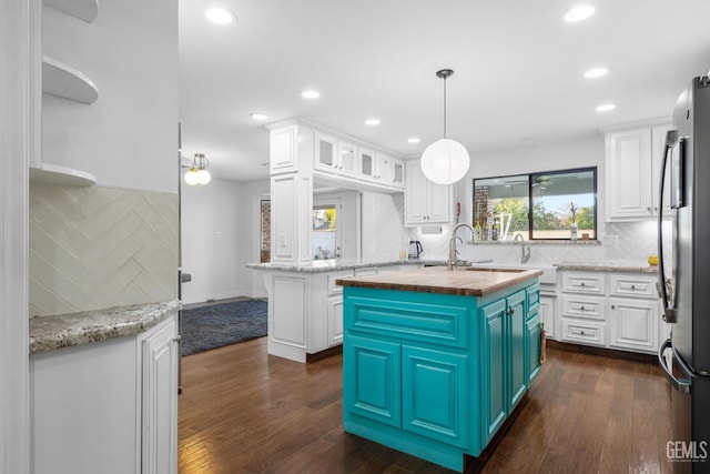 kitchen featuring blue cabinetry, a center island with sink, white cabinetry, and freestanding refrigerator