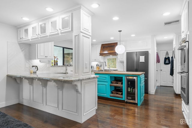 kitchen with custom range hood, a breakfast bar, decorative light fixtures, a peninsula, and white cabinetry