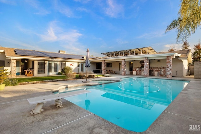 view of swimming pool featuring a bar, a pool with connected hot tub, a diving board, and a patio