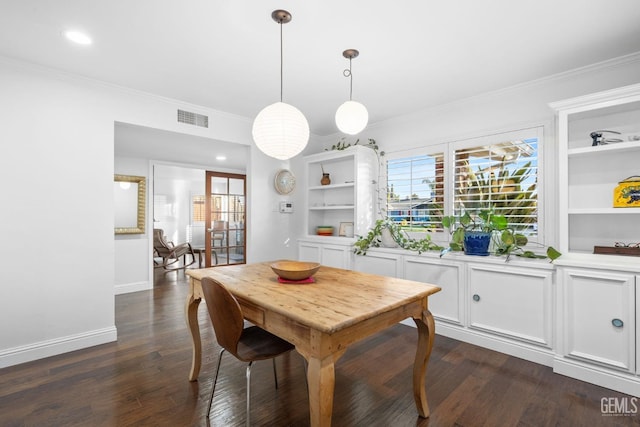 dining space featuring dark wood-type flooring, visible vents, and crown molding