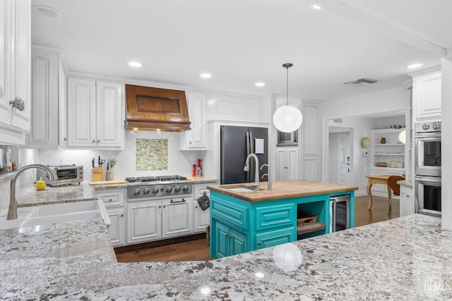 kitchen with appliances with stainless steel finishes, white cabinetry, and a sink