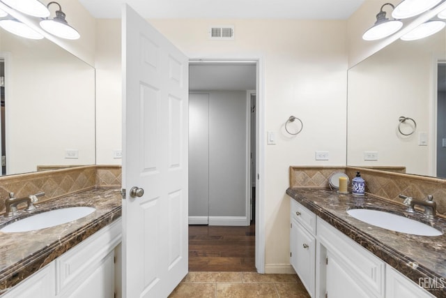 bathroom featuring two vanities, decorative backsplash, and a sink