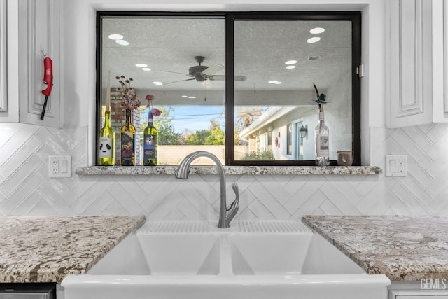 room details featuring a ceiling fan, light countertops, a sink, and backsplash