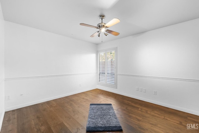 spare room featuring dark wood-style floors, ceiling fan, and baseboards