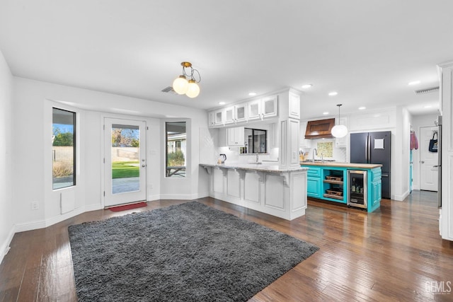 kitchen with decorative light fixtures, glass insert cabinets, white cabinetry, a peninsula, and a kitchen breakfast bar