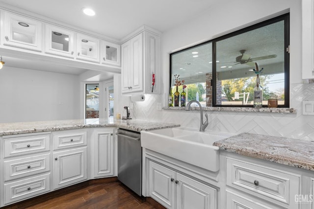 kitchen featuring stainless steel dishwasher, glass insert cabinets, a sink, and white cabinetry