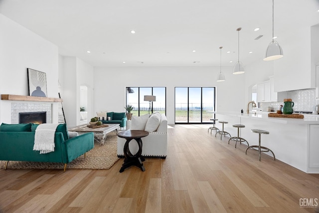 living area with recessed lighting, a tiled fireplace, and light wood finished floors