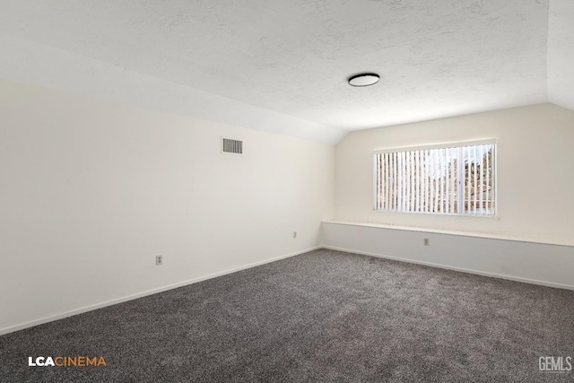 unfurnished room with carpet floors, a textured ceiling, and vaulted ceiling