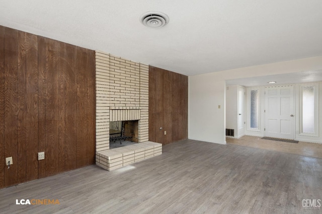 unfurnished living room featuring wooden walls, a fireplace, and hardwood / wood-style floors