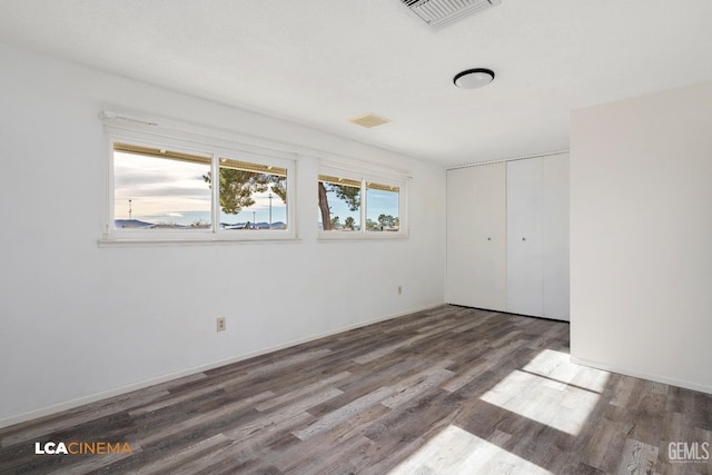 unfurnished bedroom featuring dark hardwood / wood-style flooring and a closet