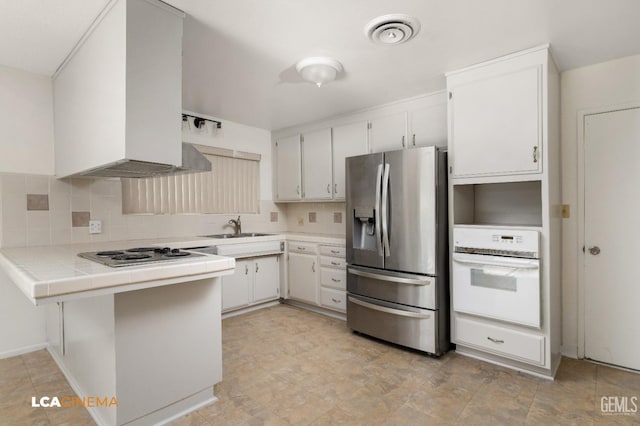 kitchen featuring white appliances, tile countertops, white cabinetry, and tasteful backsplash