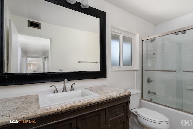 full bathroom featuring vanity, toilet, and bath / shower combo with glass door