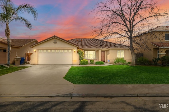 view of front facade featuring stucco siding, a lawn, an attached garage, driveway, and a tiled roof