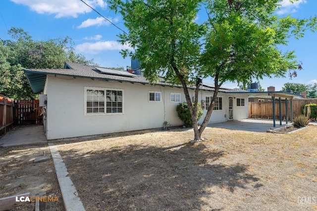 2109 Custer Ave, Bakersfield, CA 93304 - back of house with a patio area, a fenced backyard, roof mounted solar panels, and stucco siding