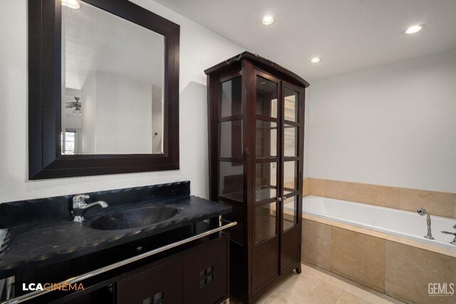 bathroom featuring tile patterned flooring, vanity, and tiled bath