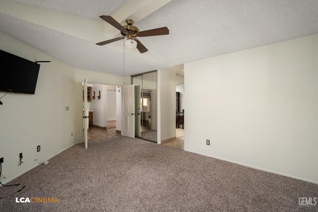 unfurnished bedroom featuring ensuite bath, lofted ceiling, carpet, ceiling fan, and a textured ceiling