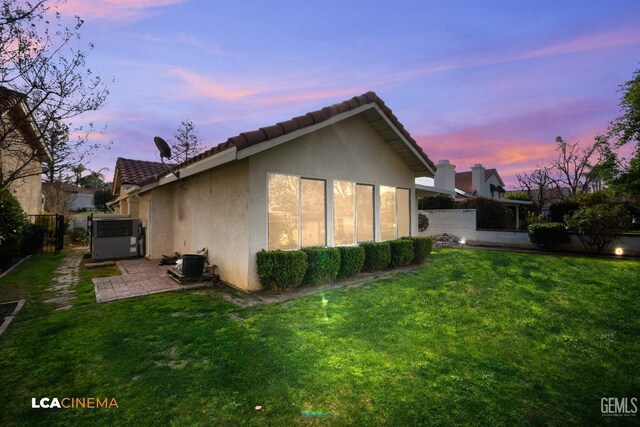 back house at dusk featuring a yard and a patio area