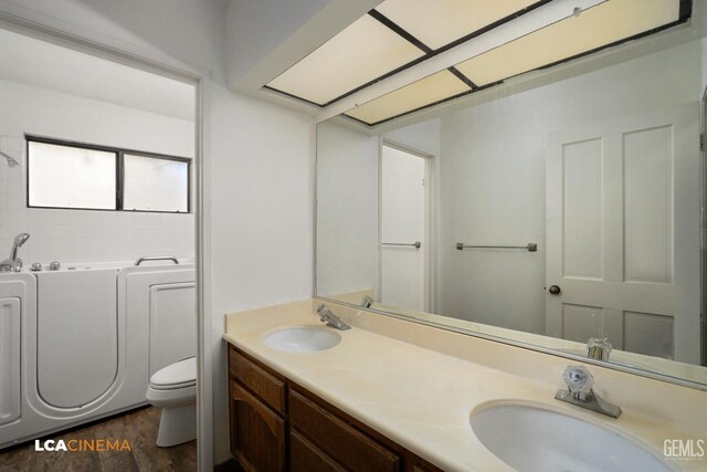 bathroom featuring hardwood / wood-style flooring, vanity, a bathing tub, and toilet