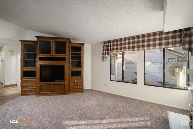 unfurnished living room featuring vaulted ceiling, carpet floors, and a textured ceiling