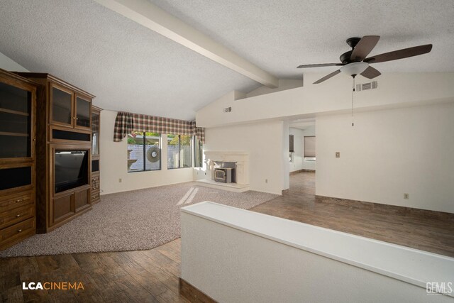 unfurnished living room featuring lofted ceiling with beams, wood-type flooring, ceiling fan, and a textured ceiling