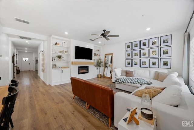 9642 Silver Falls Ln, Shafter, CA 93263 - living area featuring a ceiling fan, light wood-type flooring, a glass covered fireplace, recessed lighting, and built in features