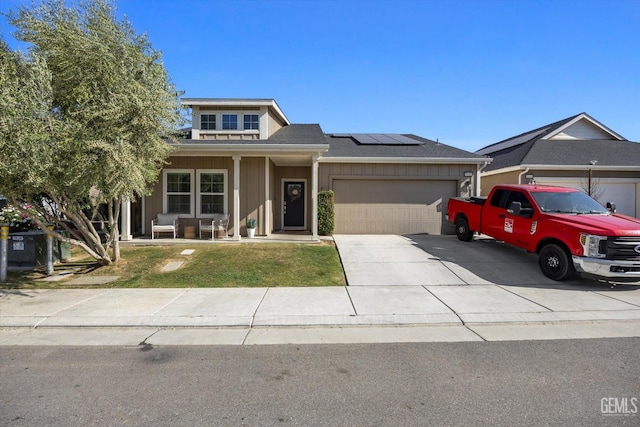 9642 Silver Falls Ln, Shafter, CA 93263 - view of front of house featuring an attached garage, roof mounted solar panels, concrete driveway, board and batten siding, and covered porch