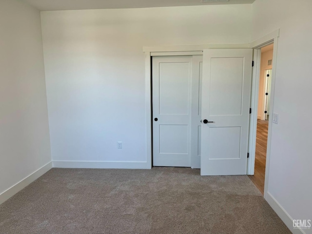 unfurnished bedroom featuring baseboards, carpet flooring, and a closet