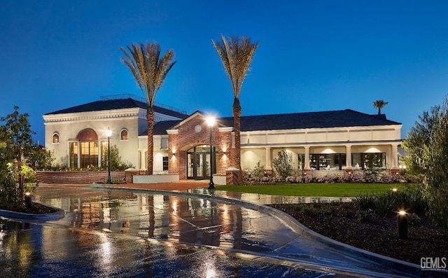 view of front facade featuring a lawn, stucco siding, and french doors