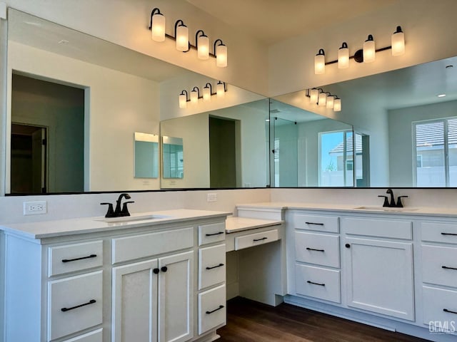full bathroom featuring a sink, wood finished floors, and two vanities