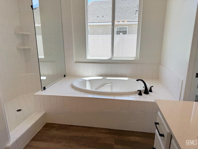bathroom featuring a garden tub, vanity, wood finished floors, and tiled shower