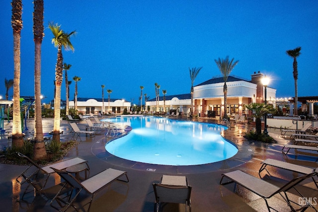 pool at night with a community pool and a patio area