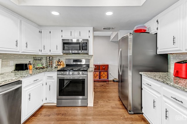 7701 Shetland Dr, Bakersfield, CA 93309 - kitchen featuring appliances with stainless steel finishes, light wood-style flooring, backsplash, light stone counters, and white cabinetry
