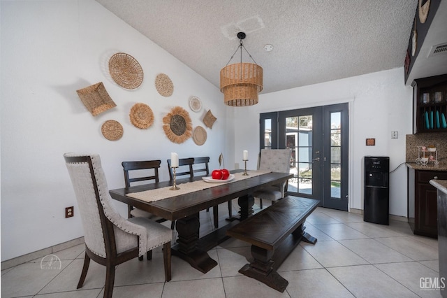 dining room featuring visible vents, vaulted ceiling, light tile patterned flooring, a notable chandelier, and a textured ceiling