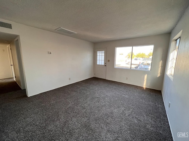 carpeted empty room featuring a textured ceiling