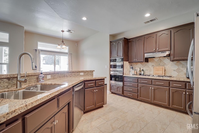 kitchen featuring visible vents, a sink, appliances with stainless steel finishes, under cabinet range hood, and backsplash