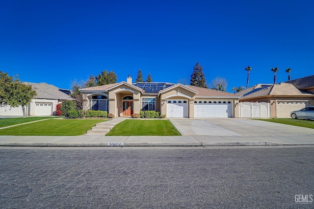 view of front of house with concrete driveway, a front yard, roof mounted solar panels, stucco siding, and a garage