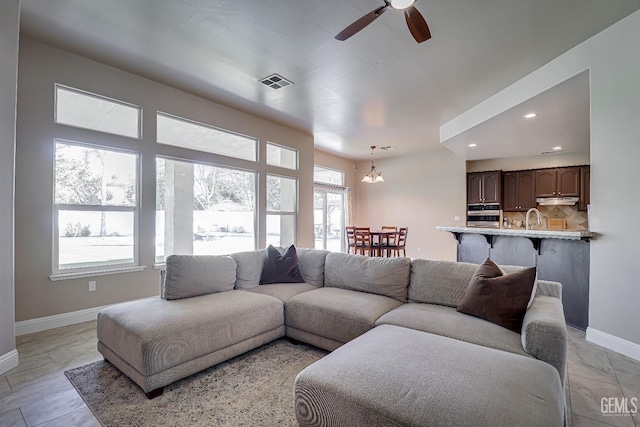 living room featuring recessed lighting, visible vents, ceiling fan with notable chandelier, and baseboards