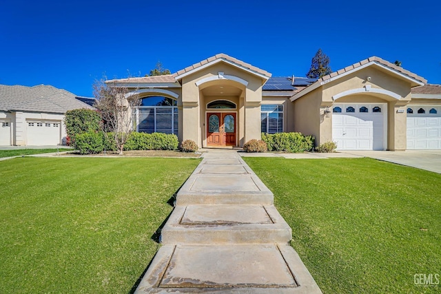 view of front of home featuring a front yard, solar panels, an attached garage, stucco siding, and french doors