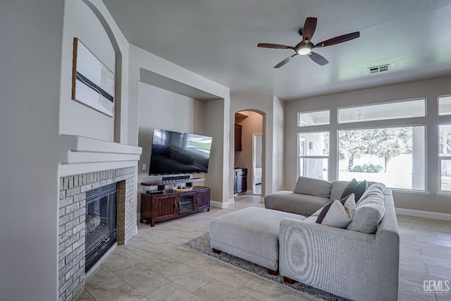 living room with visible vents, arched walkways, a fireplace, baseboards, and ceiling fan