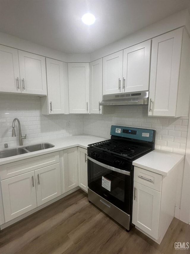 kitchen featuring white cabinets, a sink, stainless steel range with gas stovetop, and under cabinet range hood