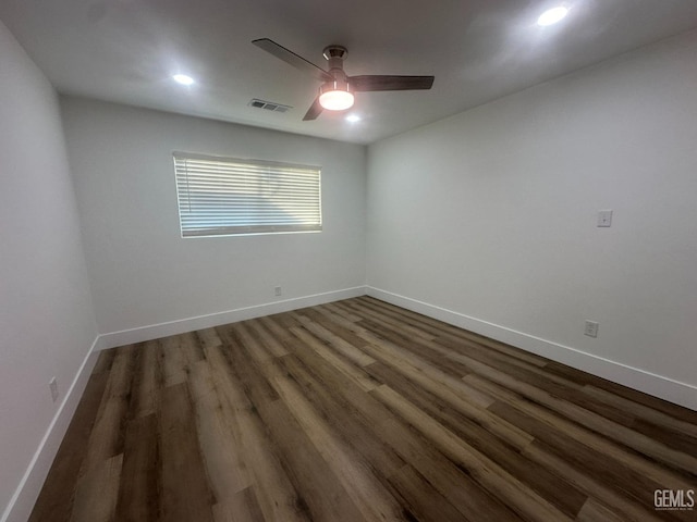 empty room with baseboards, visible vents, dark wood finished floors, and a ceiling fan