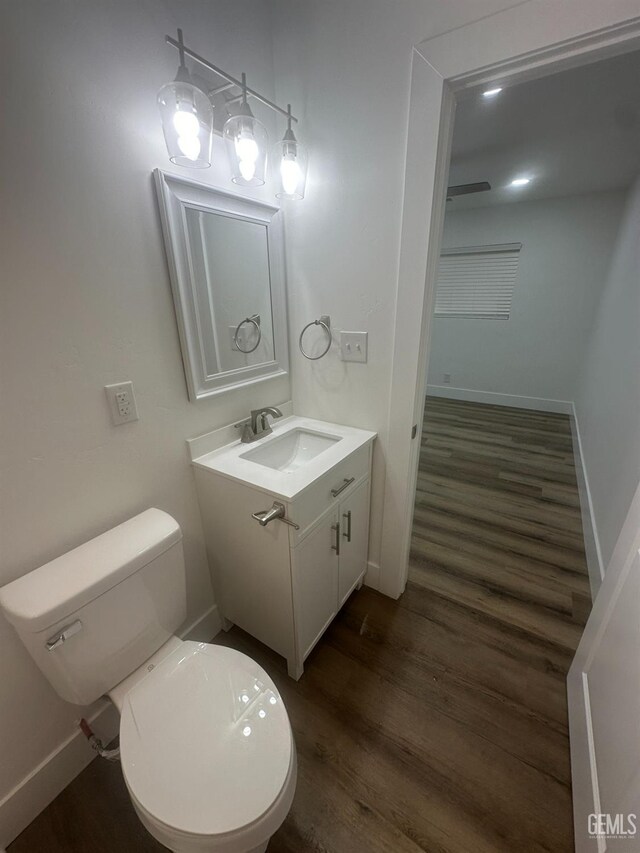 bathroom with toilet, baseboards, wood finished floors, and vanity