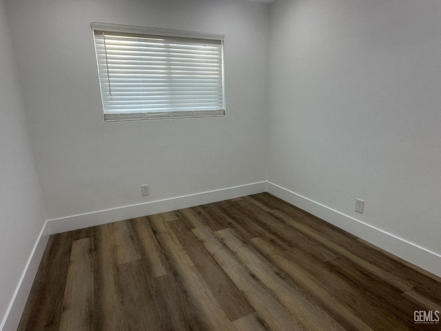 empty room featuring baseboards and dark wood-style flooring