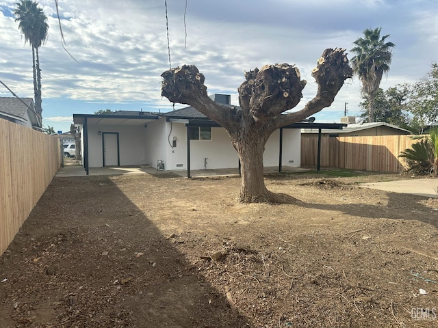 back of house featuring a carport and fence