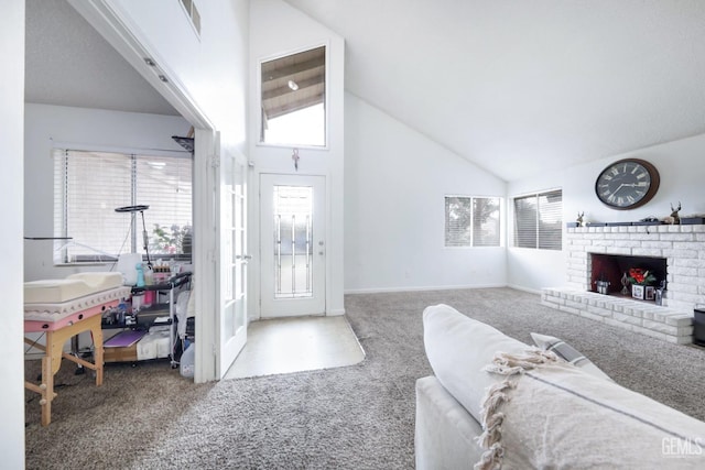 carpeted entryway with plenty of natural light, high vaulted ceiling, and a brick fireplace