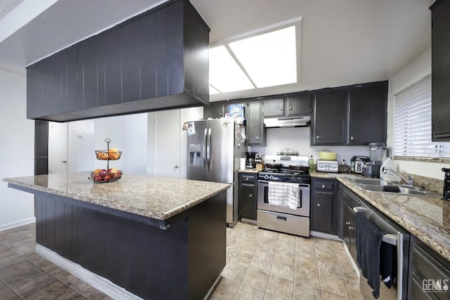 kitchen featuring light stone counters, stainless steel appliances, a kitchen bar, and sink