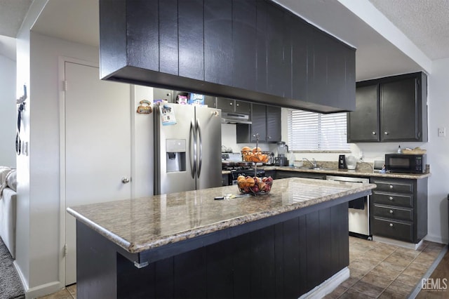 kitchen with sink, a kitchen island, black appliances, stone countertops, and light tile patterned flooring